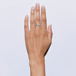 Hand wearing a silver ring on a light gray background